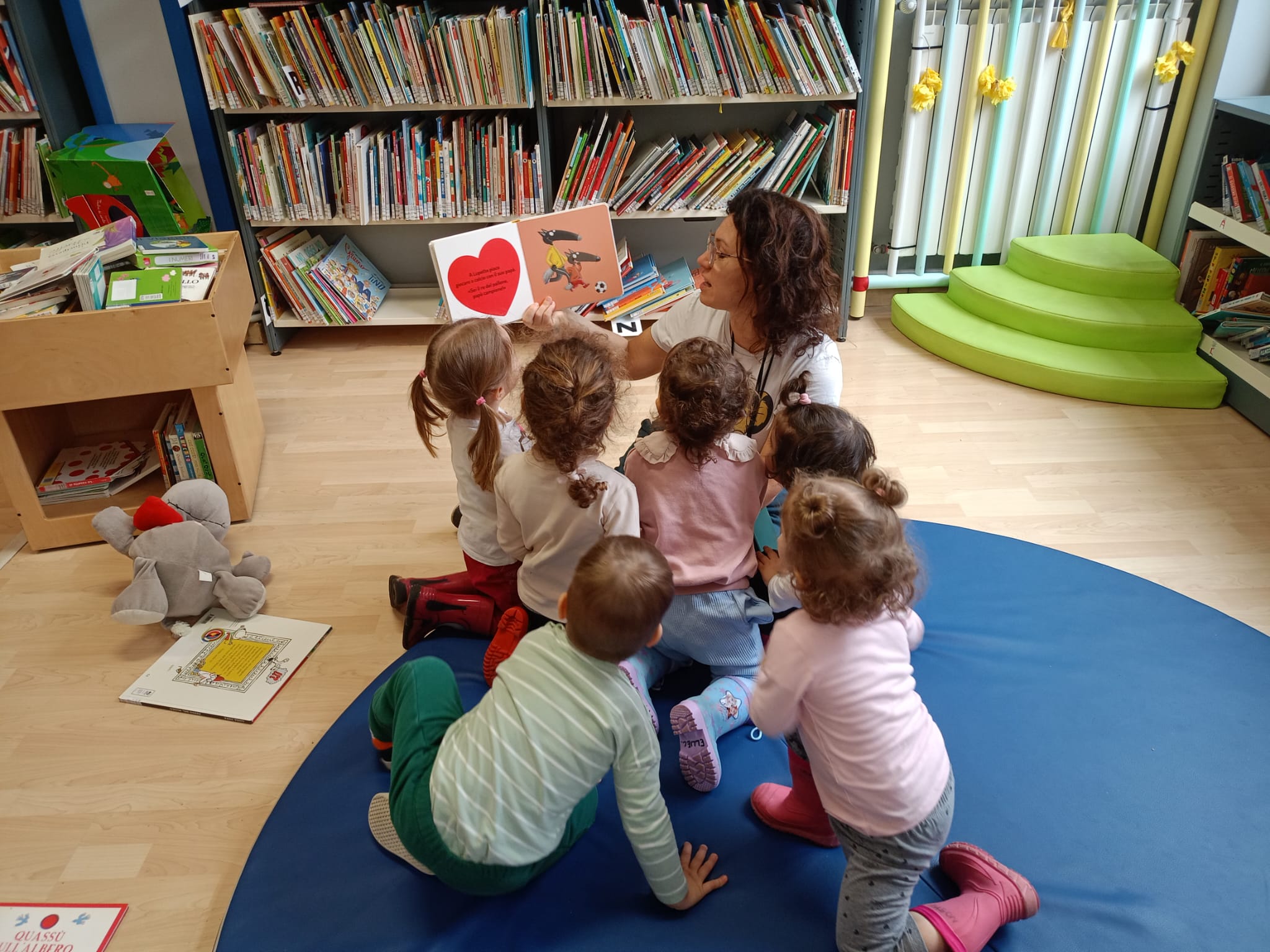 Insegnante legge un libro a un gruppo di bambini in classe